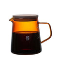 Clear glass coffee maker with amber-colored interior and wooden lid on a white background