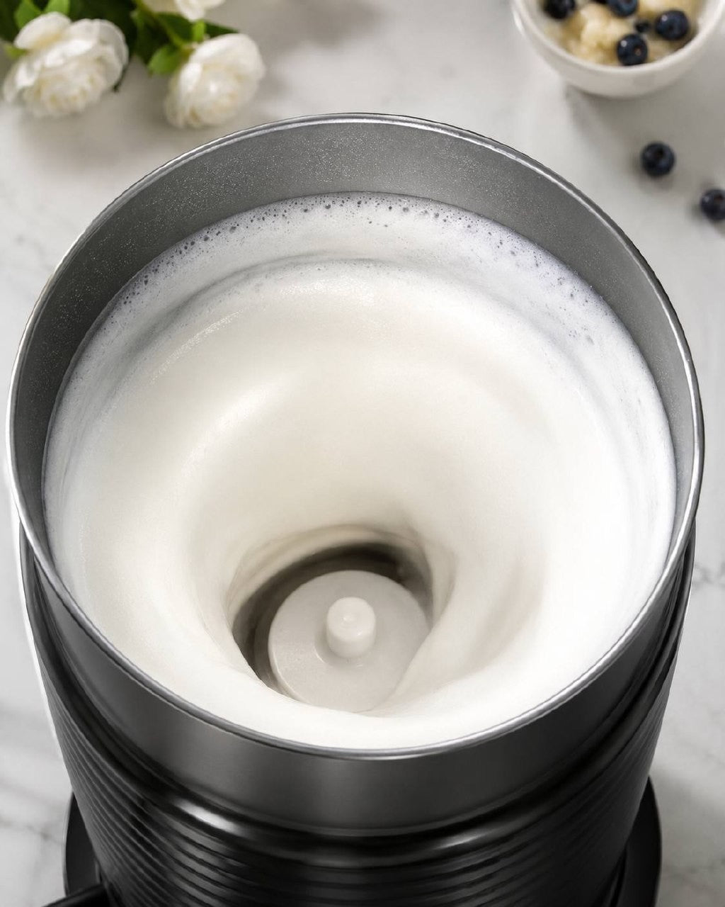Close up of thick milk foam inside the black automatic electric milk frother container.