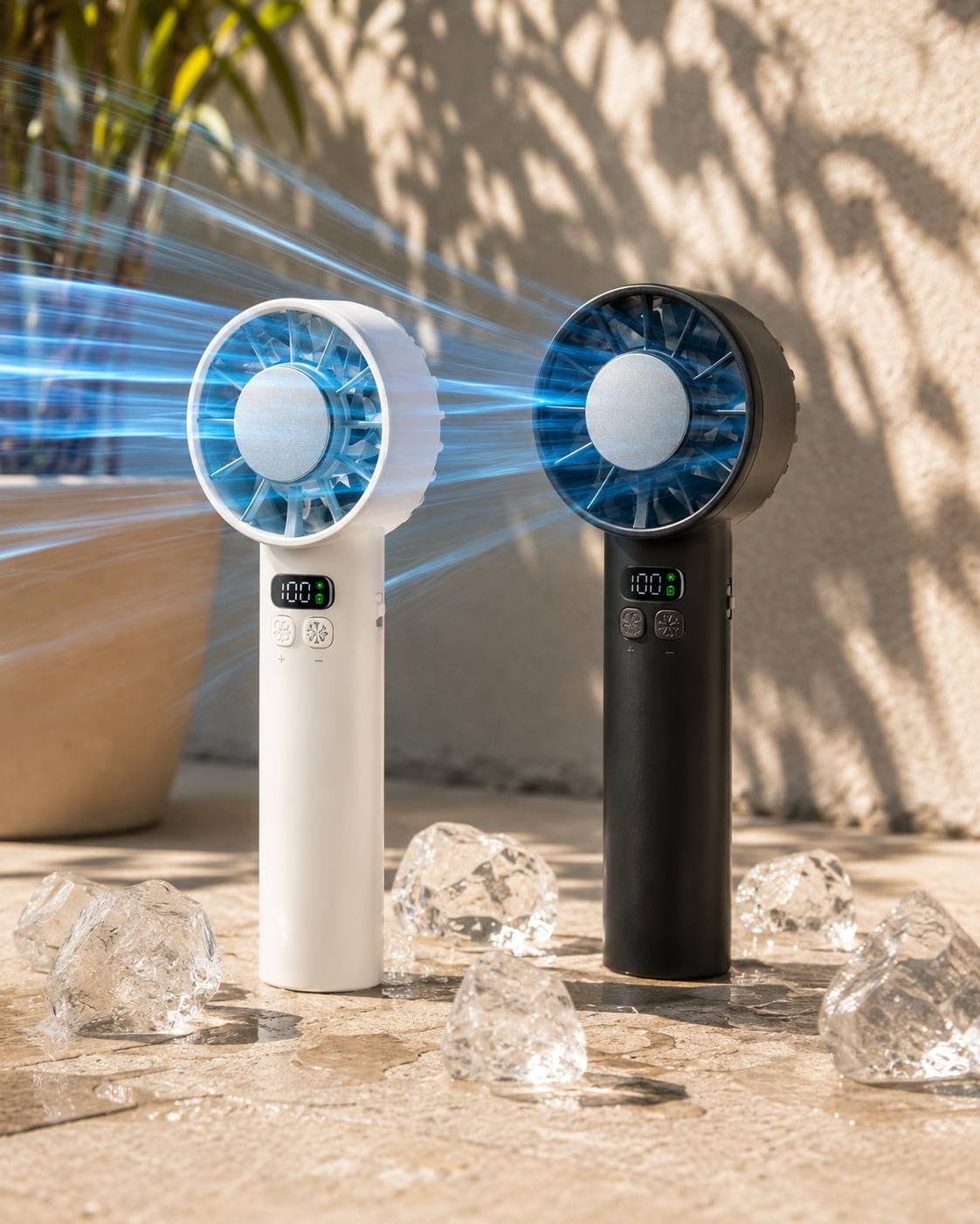 Studio product shot of black and white portable handheld cooling fans placed on a stone surface surrounded by melting ice cubes under bright sunlight.
