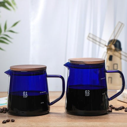 Two blue glass pitchers with wooden lids on a wooden surface.