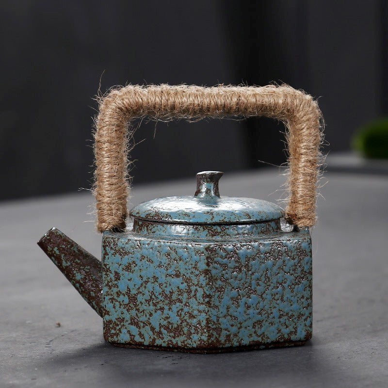 Vintage-style blue teapot with a textured handle on a dark background