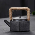 Black textured teapot with a jute handle on a dark background
