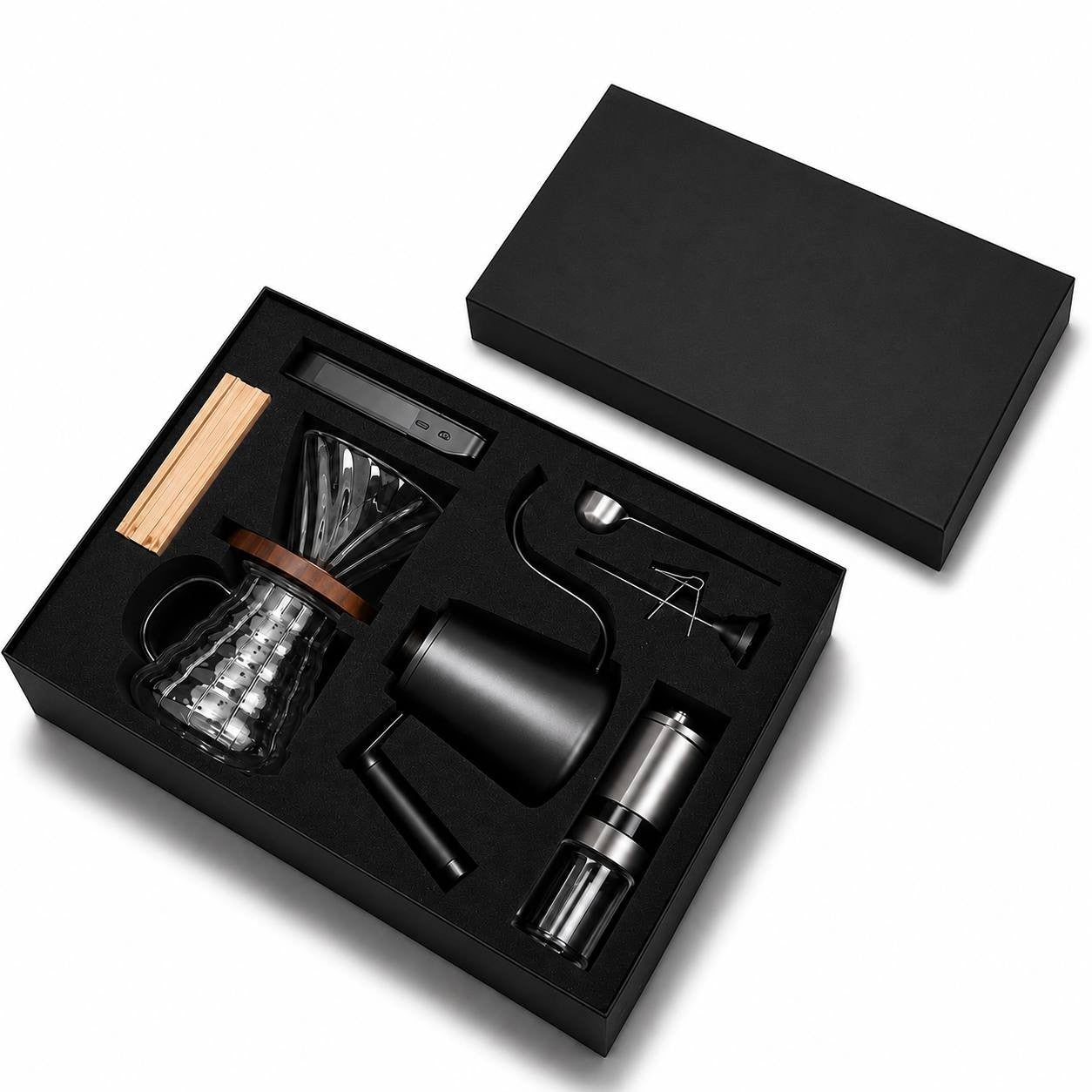 A black gift box containing a glass coffee dripper, gooseneck kettle, manual grinder, and accessories on a white background.