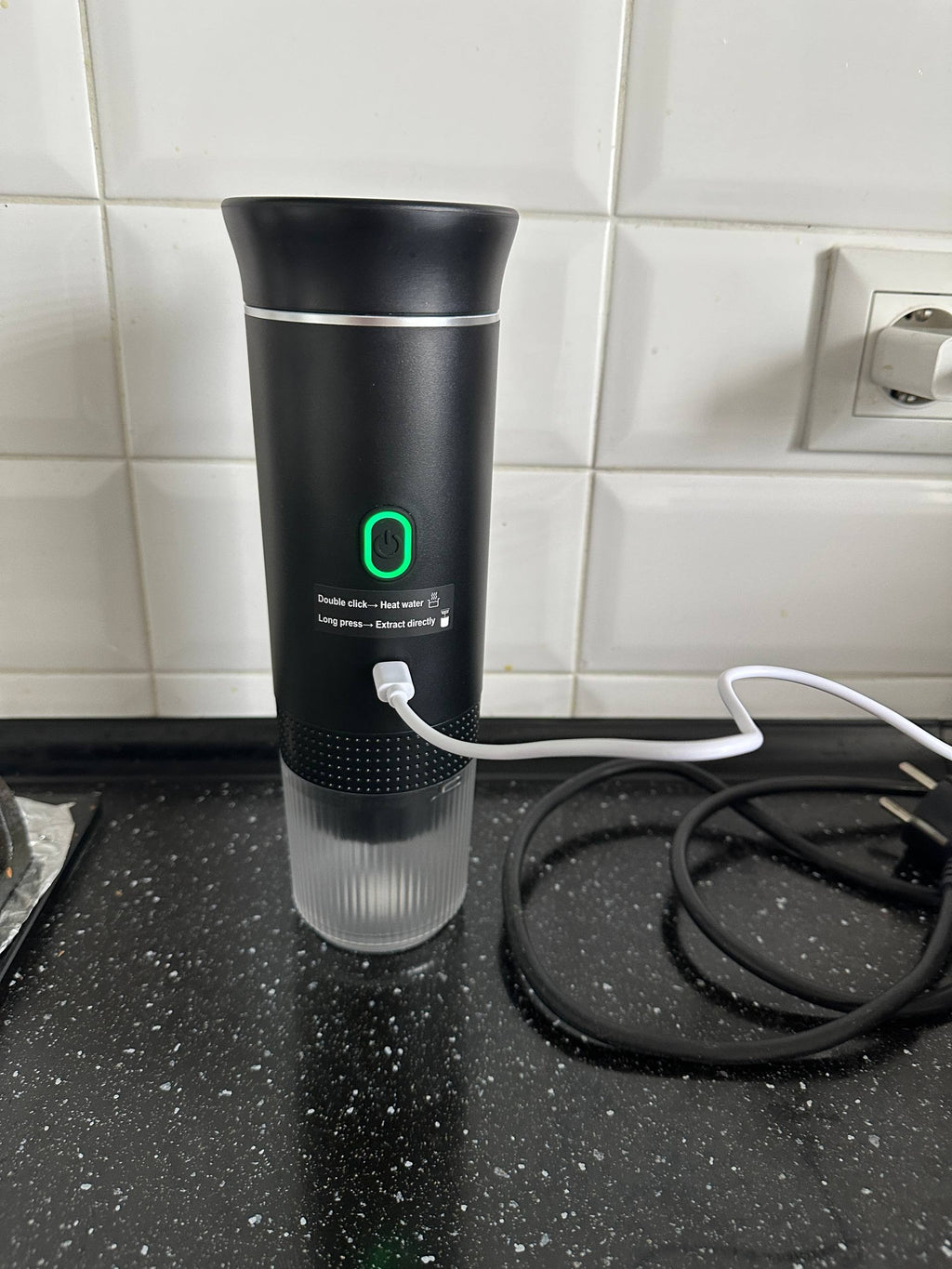 Black electric portable espresso machine charging on a kitchen countertop