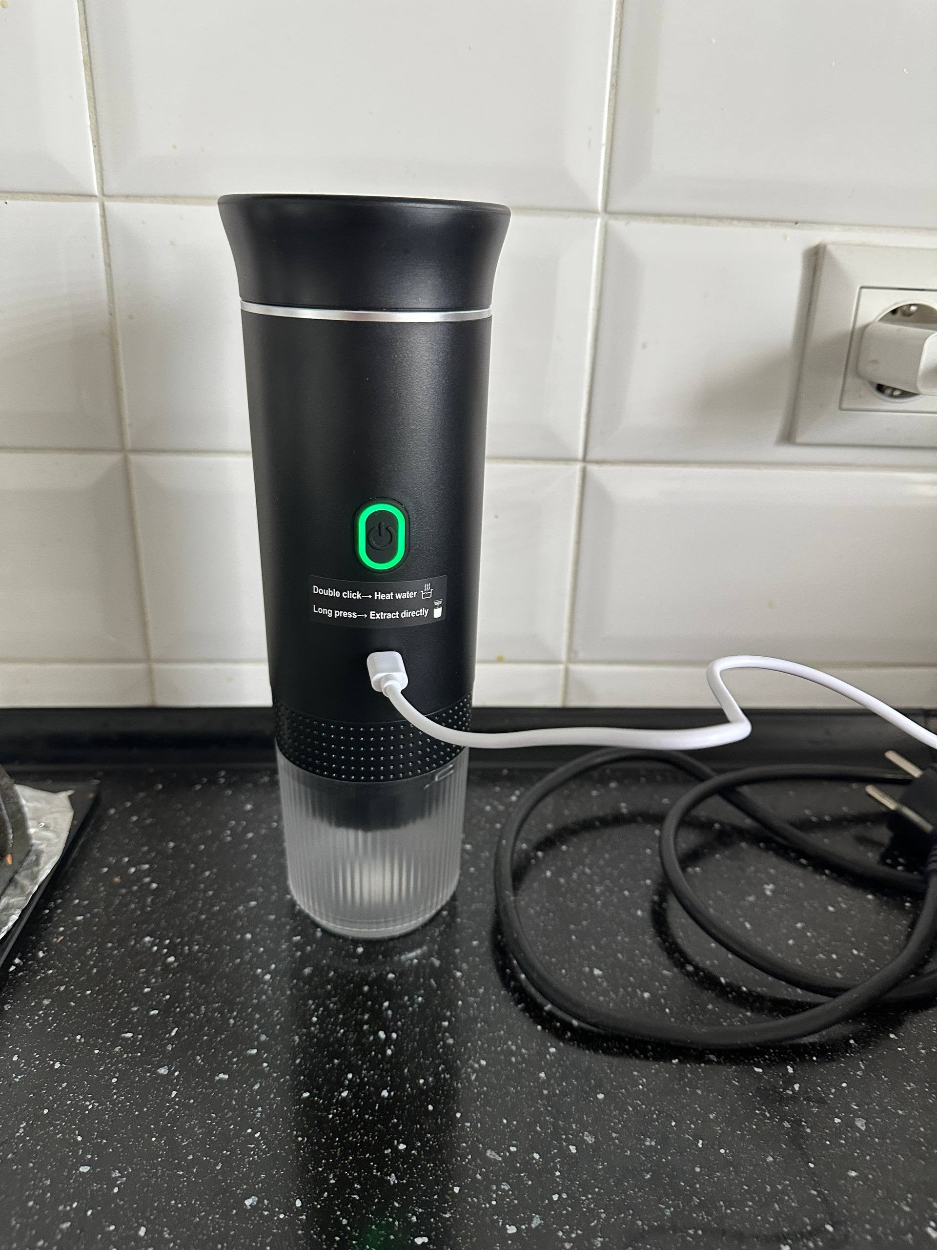 Black electric portable espresso machine charging on a kitchen countertop