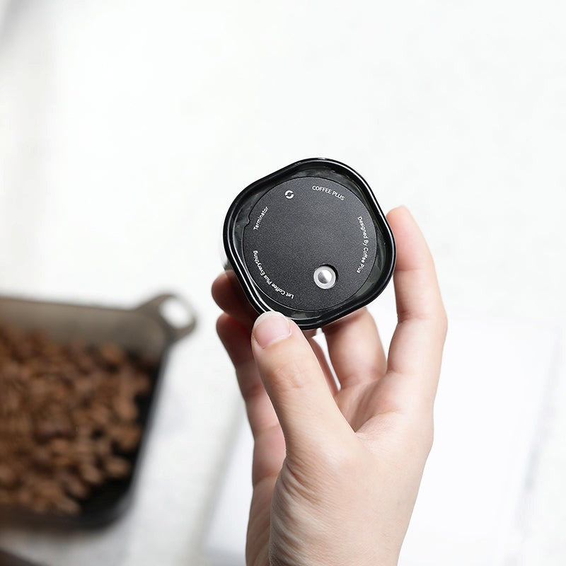 Hand holding a black pet food measuring device with a blurred background