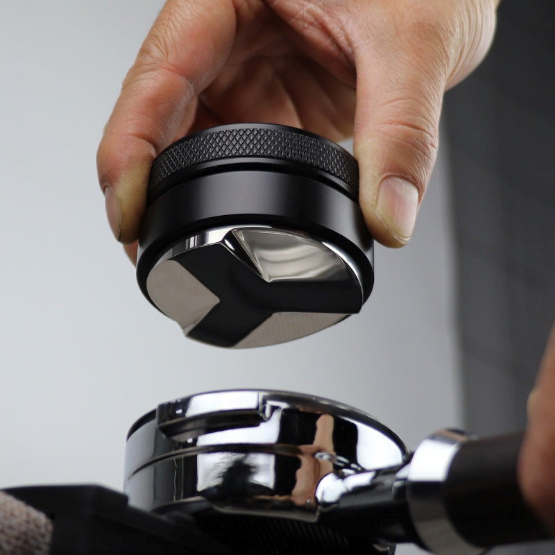 Hand holding a black and silver coffee grinder against a neutral background