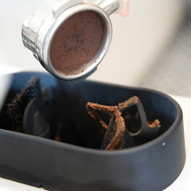 Coffee grinder with coffee beans being ground into a black container