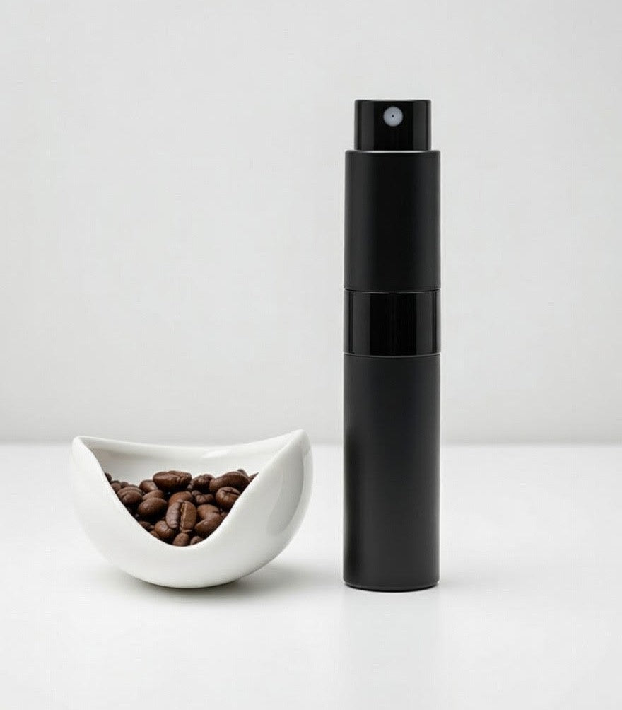 Black spray bottle next to a bowl of coffee beans on a white background