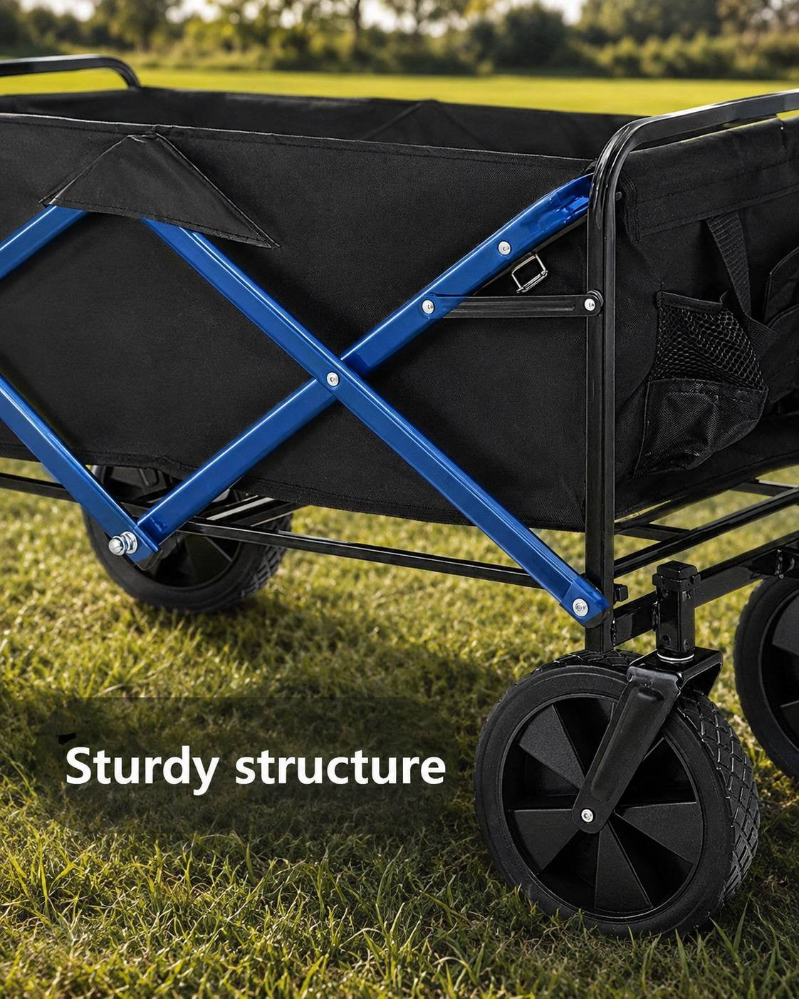 Close-up of the sturdy blue and black metal frame and wheels of a folding utility wagon standing on green grass.