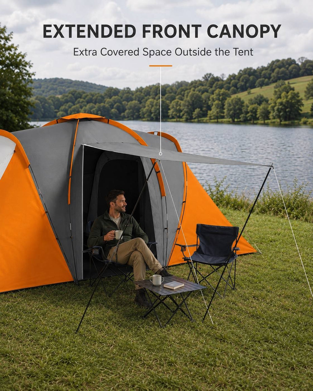 Man sitting in a camping chair under the extended front canopy of a large camping tent by a lake, holding a mug next to a small table.