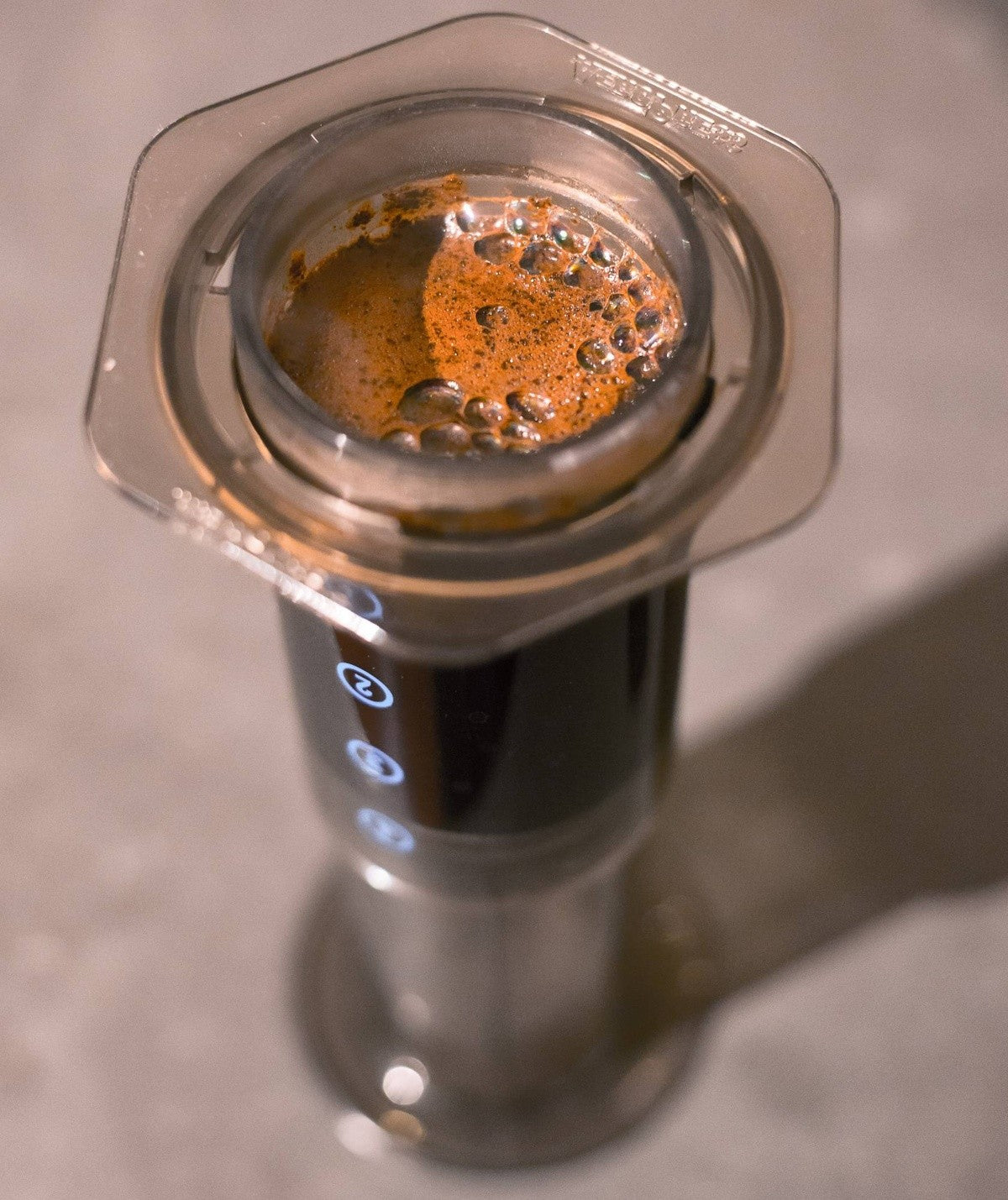 Close-up of rich coffee extraction and crema inside a handheld immersion coffee maker.