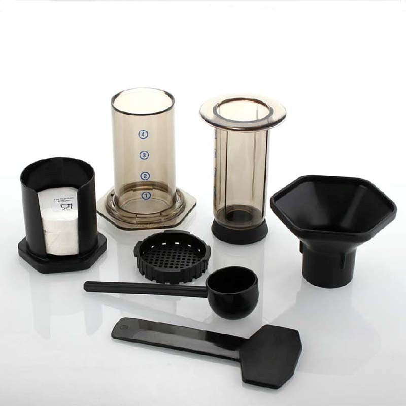 Set of coffee brewing components including a glass container, black funnel, and various other parts on a white background.