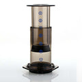 Clear cylindrical coffee maker with black base on a white background