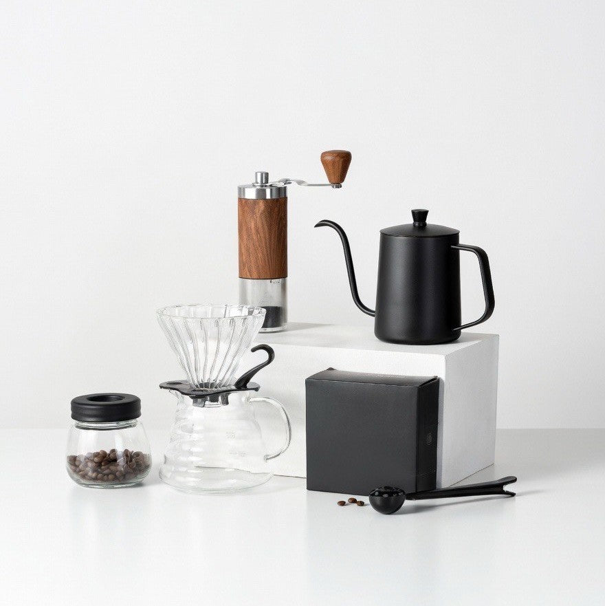 Collection of coffee-making equipment including a grinder, kettle, and filter on a white background