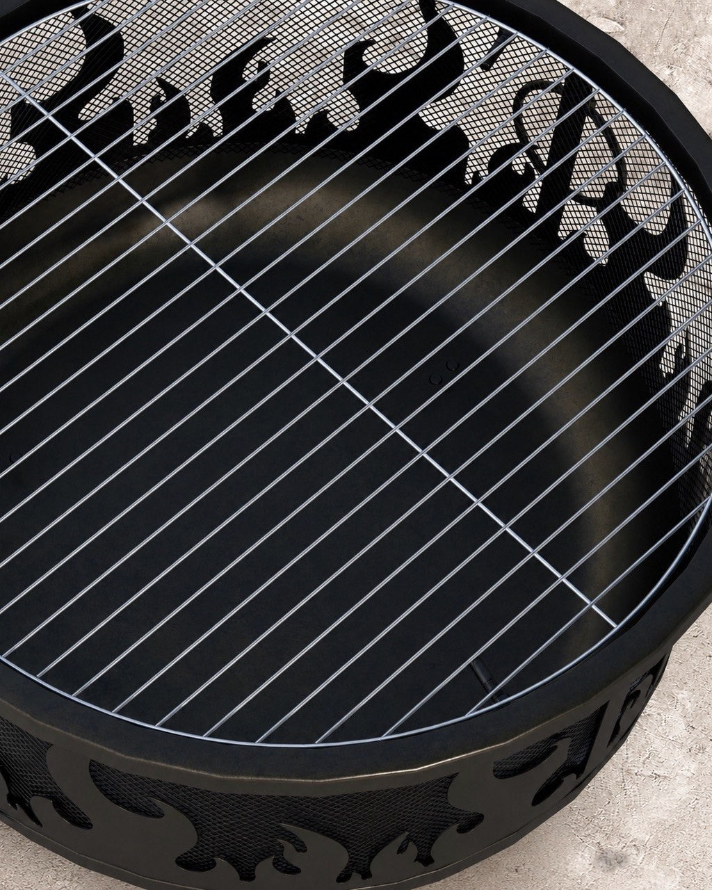 Close-up top view of the internal steel wire mesh grill grate placed inside a black metal fire pit with a flame-cut outer wall.