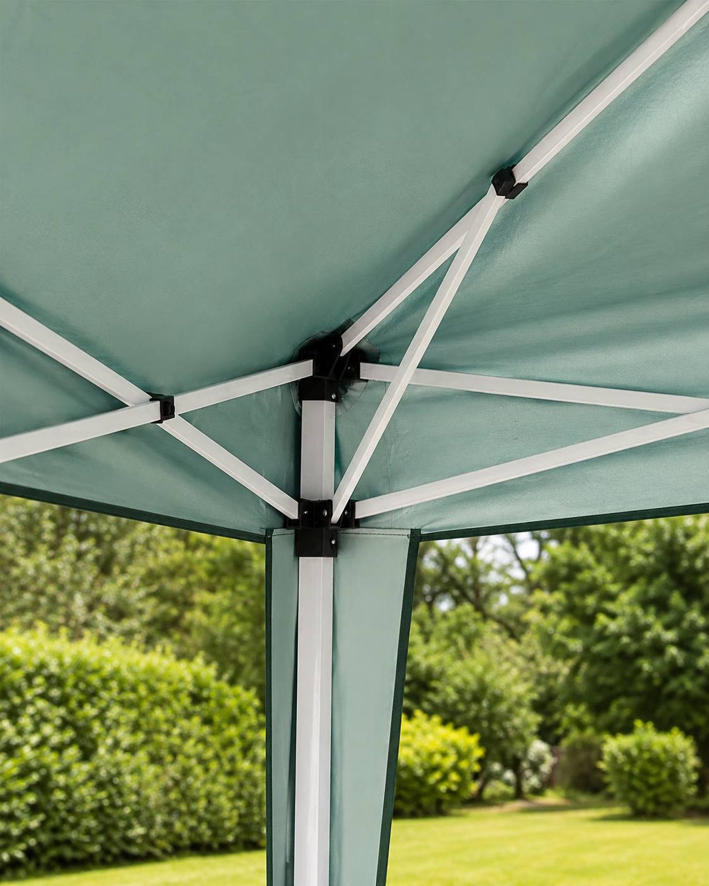 Close-up view of the white metal frame joints, struts, and upper mechanism under the green fabric canopy of a pop-up gazebo.