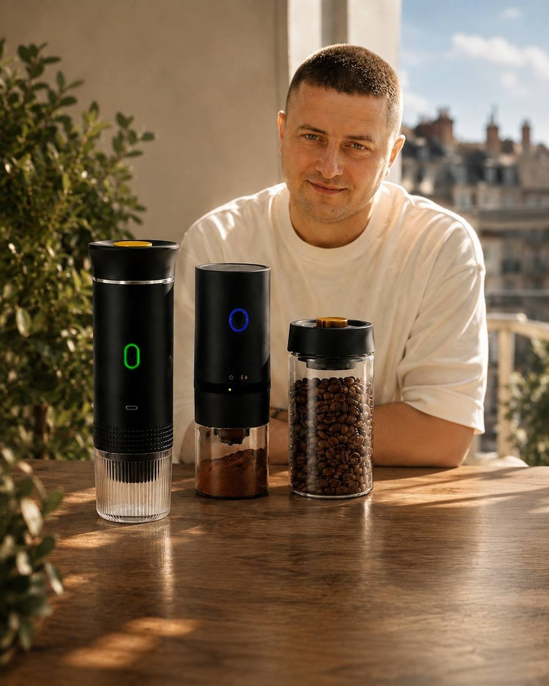 Man standing next to a portable coffee maker, a coffee grinder, and a coffee bean storage container on a table.