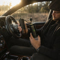 Person using a portable manual coffee grinder and coffee maker inside a car for brewing coffee while traveling