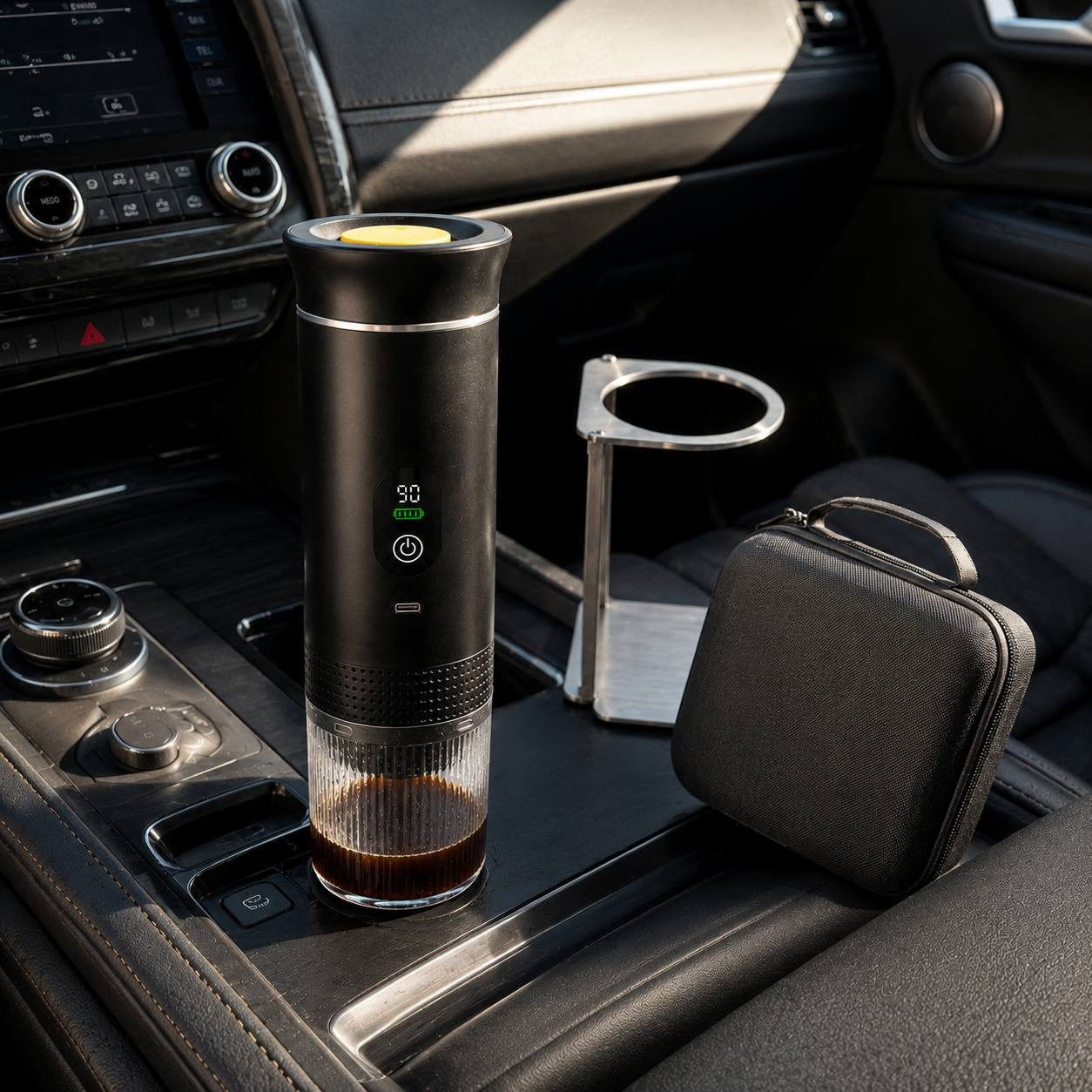 Portable electric espresso maker with travel stand and carrying case set up in a car.