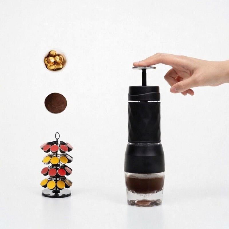 Hand using a black manual coffee grinder with coffee beans and pods on a white background