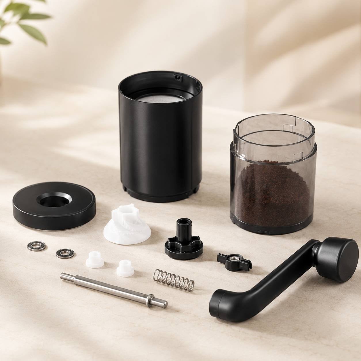 A disassembled manual coffee grinder with its components laid out on a table.