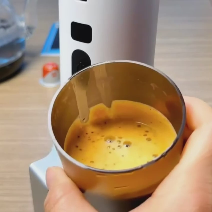Instructional video demonstrating the preparation of espresso using both coffee capsules and ground coffee with a portable espresso machine.