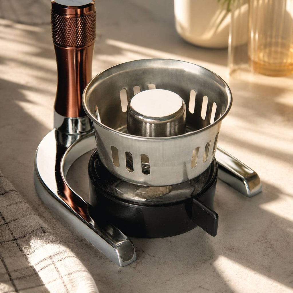 Close-up of a chrome and copper metal burner base with a stainless steel windscreen housing for a syphon coffee brewer.